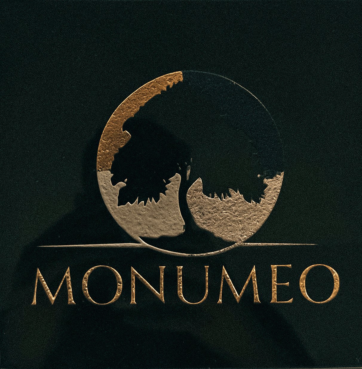 Logo MONUMEO gravé sur granit noir : une partie à la feuille d’or, une partie en peinture dorée